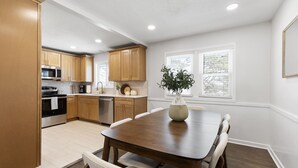 Una cocina moderna con armarios de madera, una mesa de comedor y un florero con una planta.