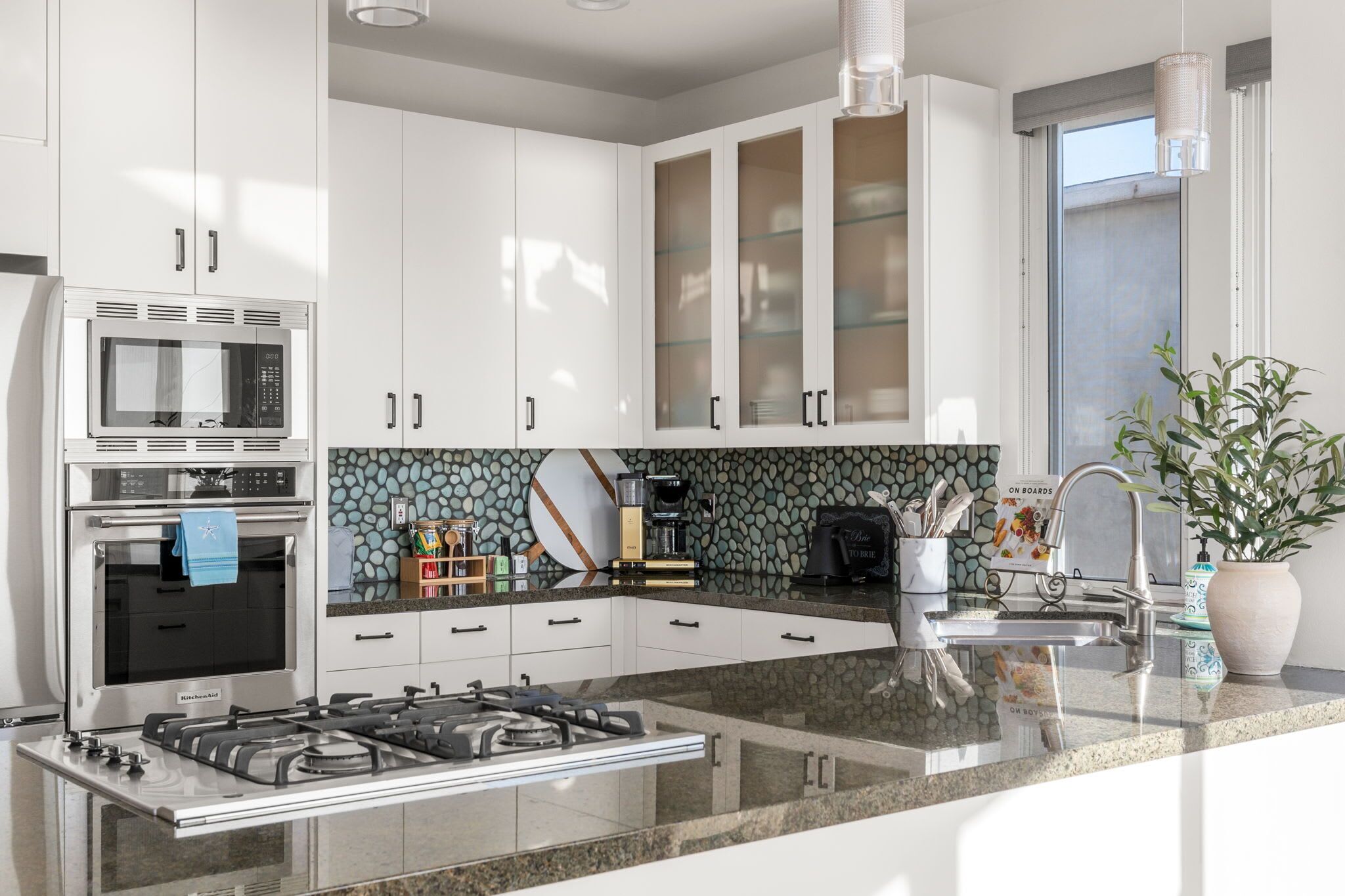 A modern kitchen with white cabinets, a built-in microwave, a gas stove, and a coffee maker.