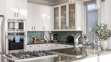 A modern kitchen with white cabinets, a built-in microwave, a gas stove, and a coffee maker.
