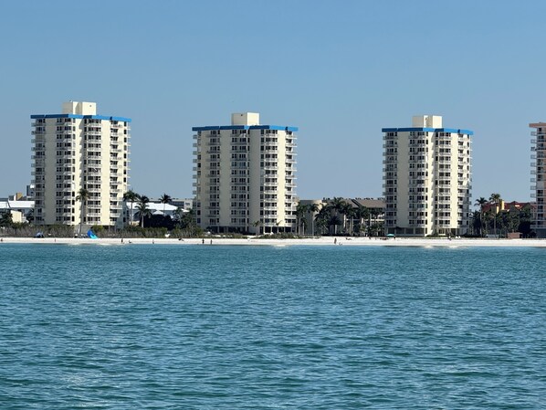 A beachfront hotel with multiple high-rise buildings, a sandy beach, and a clear blue sky.