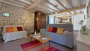 Ein Wohnzimmer mit Steinsäulen, Holzbalkendecke, einer Couch, einem Couchtisch und einem Teppich.