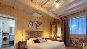 Ein Schlafzimmer mit einem großen Bett, einer Waschmaschine und einem Spiegel im anliegenden Raum.