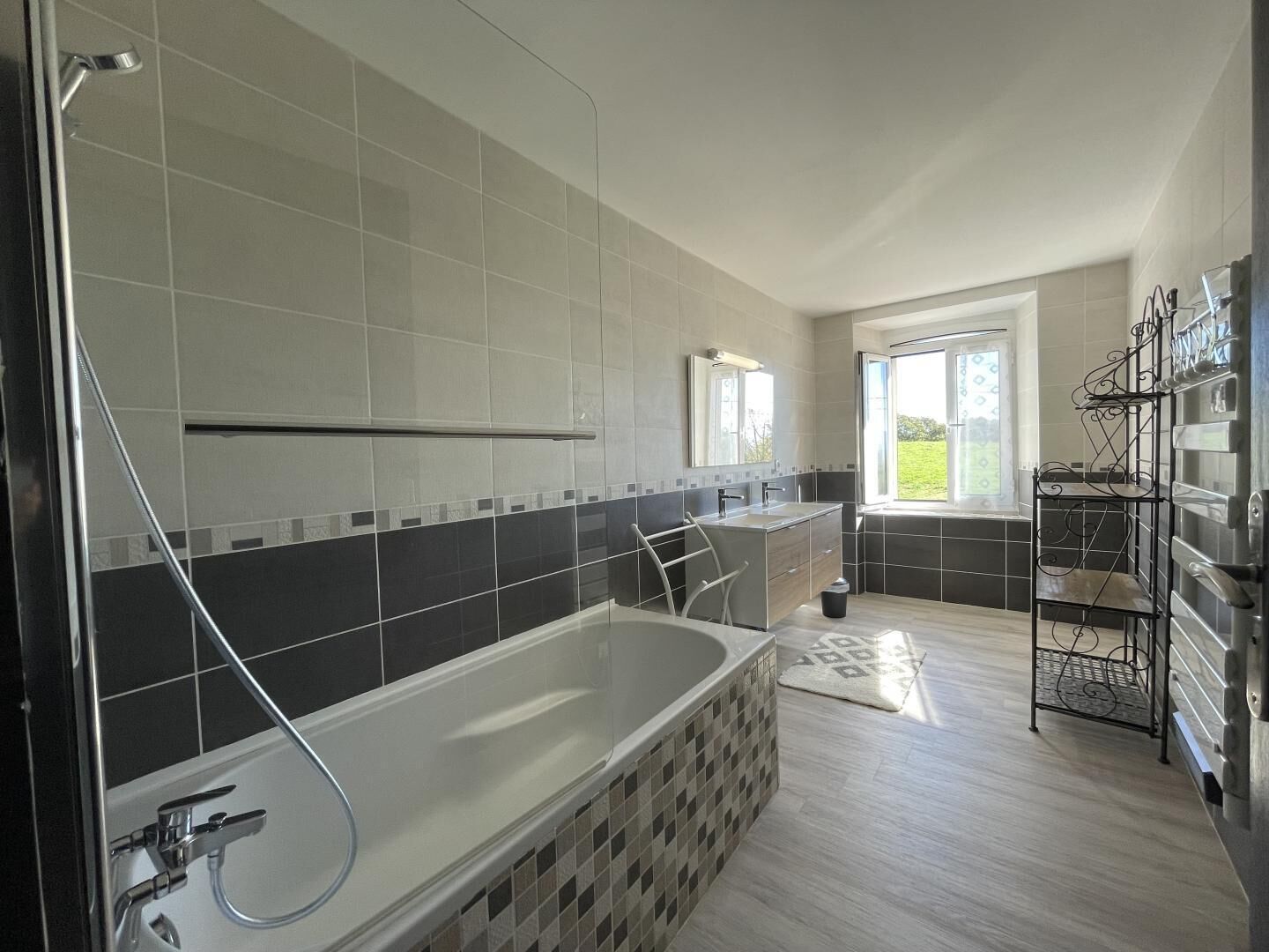 A modern bathroom with a large bathtub, a shower, and a vanity with a mirror.