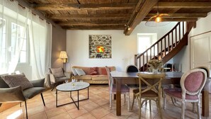 Ein gemütliches Wohnzimmer mit Holzboden, einer Wanddekoration aus Stein, einem Essbereich mit Tisch und Stühlen sowie einer Treppe.
