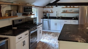 A kitchen with white cabinets, a black countertop, a stove, and a dishwasher. - Hay Loft Apartment in Barn - Goshen (Goshen)