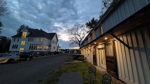 A two-story building with a porch and a table and chairs outside. - Hay Loft Apartment in Barn - Goshen (Goshen)