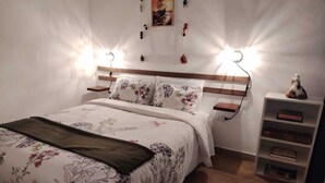 Un letto rifatto con cura, lenzuola a motivi floreali, una testiera in legno e lampade sui comodini.