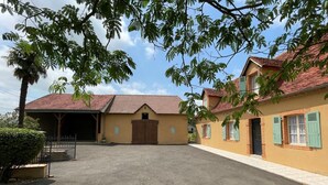 Un bâtiment avec un toit recouvert de tuiles rouges et une zone abritée dotée d’une porte en bois.