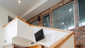 Une cuisine moderne dotée d’un îlot central intégré, de tabourets de bar en bois et d’un escalier avec une rampe en bois.