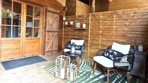 Una baita in legno con un'ampia porta scorrevole, un'area pranzo con sedie e tavolo, e un lampadario.