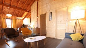 Accogliente interno di una baita in legno, con zona pranzo, divano e tavolino con una rivista.