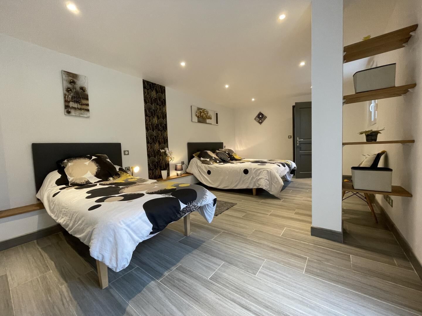 A modern bedroom with two beds, a large mirror, and a built-in shelf.