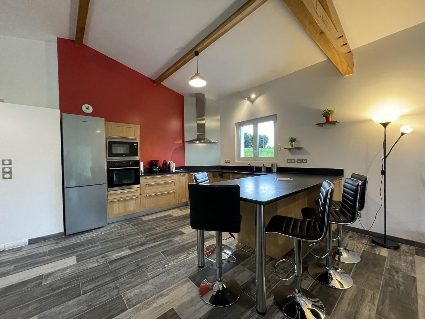 Een moderne keuken met een centraal eiland, barkrukken en een inbouwoven.