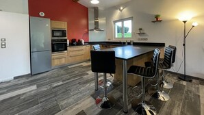Een moderne keuken met een centraal eiland, barkrukken en een inbouwoven.