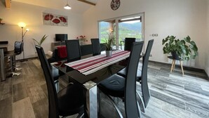 Een moderne eetruimte met een tafel voor zes personen, omringd door zwarte stoelen. Een groot raam biedt uitzicht op het landschap.
