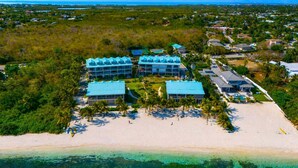Et strandhotel med flere bygninger med blå tage, en sandstrand og palmer.