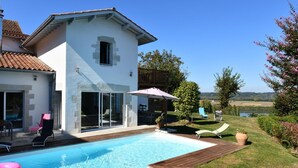 Una casa amb piscina, mobiliari exterior i vistes al camp.