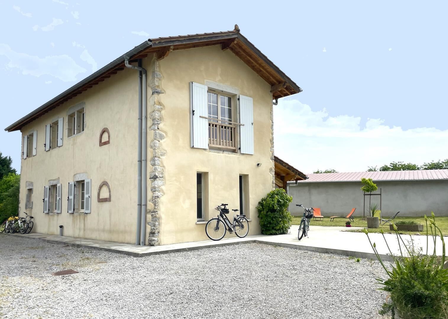 Una casa a due piani con facciata in pietra, diverse finestre e un vialetto sterrato.