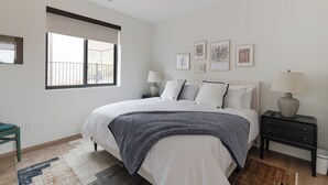 A bedroom with a large bed, a nightstand, a window, and wall art. - The Casita At Casa Estrella (Sedona)