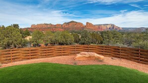 A fenced outdoor area with a grassy foreground and a view of red rock formations in the background. - The Casita At Casa Estrella (Sedona)