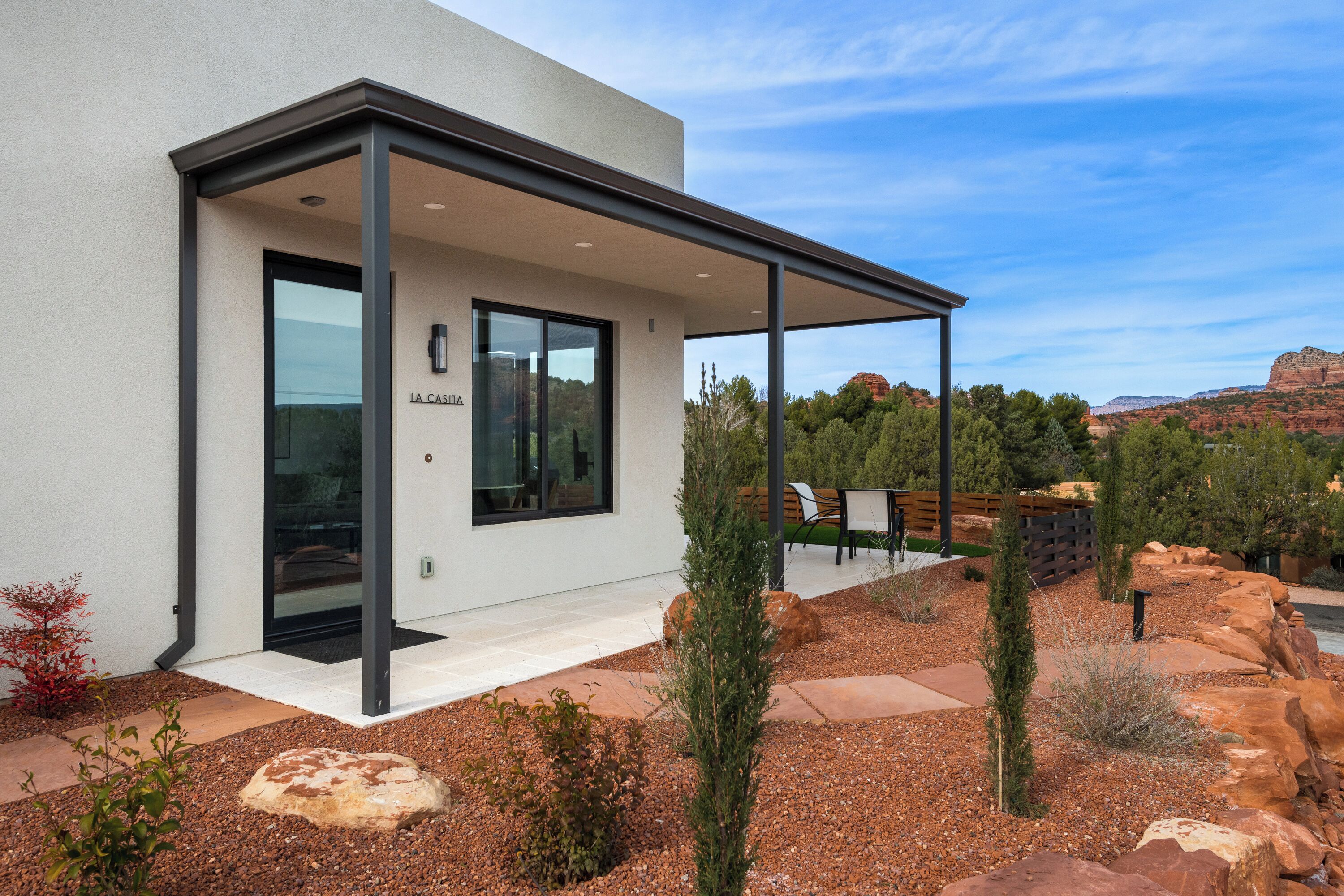 Un bâtiment moderne doté d’un patio couvert, d’une porte vitrée et d’une enseigne indiquant « LA CASA ».