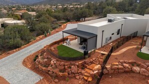 A modern house with a patio, a stone retaining wall, and a view of a hilly landscape. - The Casita At Casa Estrella (Sedona)