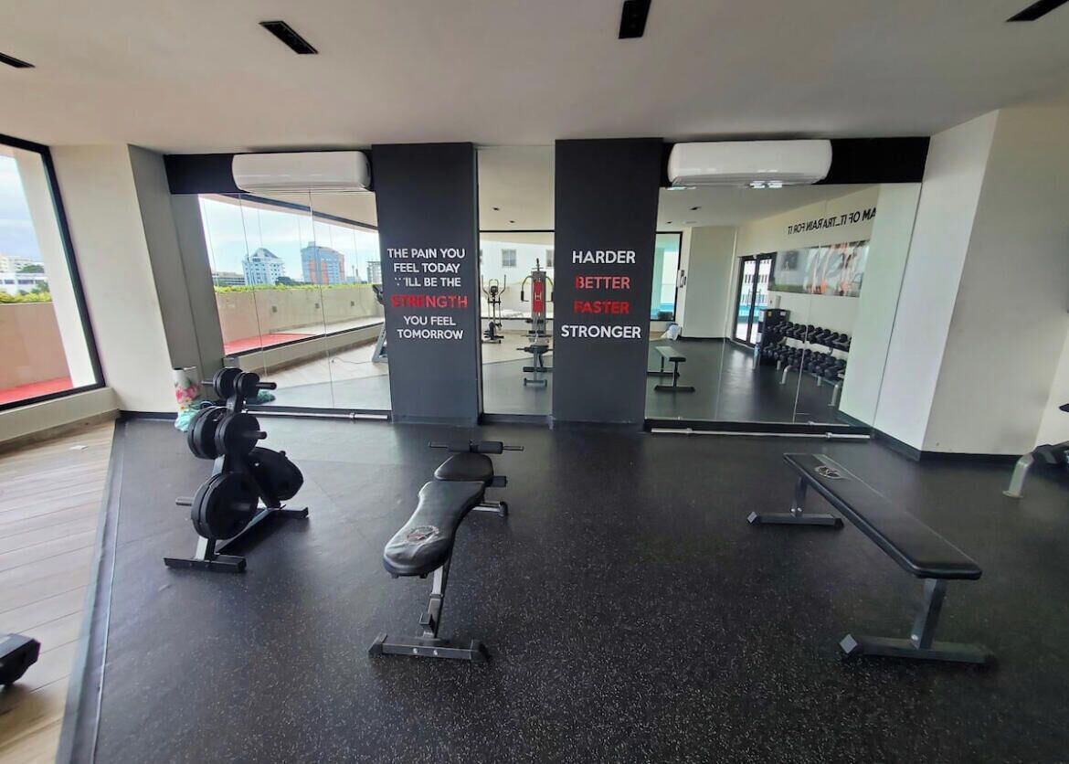 Ett gym med utrustning för styrketräning, träningsbänkar och motiverande citat på väggarna.