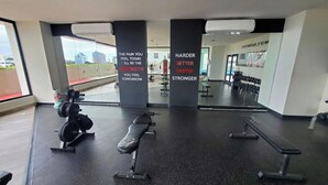Une salle de sport équipée de matériel de musculation, de bancs et dont les murs sont ornés de citations motivantes.