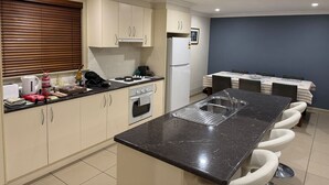 A modern kitchen with a central island, a built-in oven, and a refrigerator.
