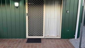 A green metal building with a sliding glass door and a small window. - Spacious & comfy studio unit “Rest Easy Mudgee” (Mudgee)