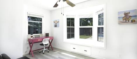 A bright room with a desk, chair, and a ceiling fan.