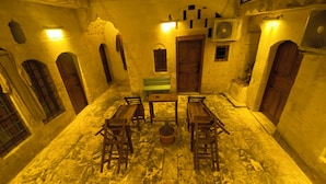 Un patio con muros de piedra, bancos de madera, una mesa y un banco con planta en maceta.