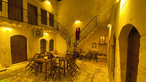 Un patio interior con una mesa y sillas de madera, una escalera y un extintor.