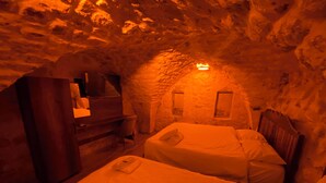 Una habitación acogedora con pared de piedra, cómoda de madera, escritorio y dos camas.