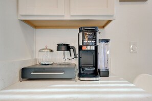 Eine Küche mit Kaffeemaschine, Wasserspender und einem Glasbehälter auf der Arbeitsplatte.