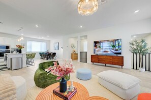 Ein modernes Wohnzimmer mit Essbereich, Küche und großem Fernsehbildschirm.