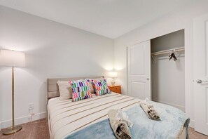 Ein Hotelzimmer mit Bett, Nachttischlampe, Kleiderschrank und einem Paar Hausschuhen auf dem Boden.
