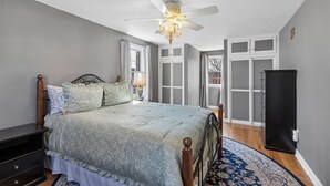 Ein Schlafzimmer mit Bett, Deckenventilator, Nachttisch, Kommode und Kleiderschrank.