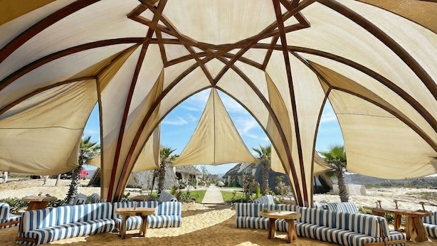 Una cabaña de playa con asientos a rayas y un marco de madera en forma de estrella.