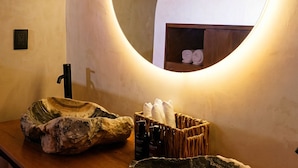 Un baño con espejo redondo, encimera de madera y toallero.