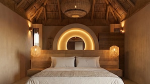 Un dormitorio con una cama grande, cabecera de madera y techo de paja.