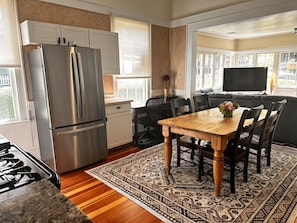 Una cocina moderna con un refrigerador de acero inoxidable, una mesa de madera con sillas y un ventanal que proporciona luz natural.