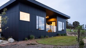 Une maison moderne à deux étages, dotée de grandes fenêtres, d’une pelouse bien entretenue et d’un chemin de pierre menant à l’entrée.