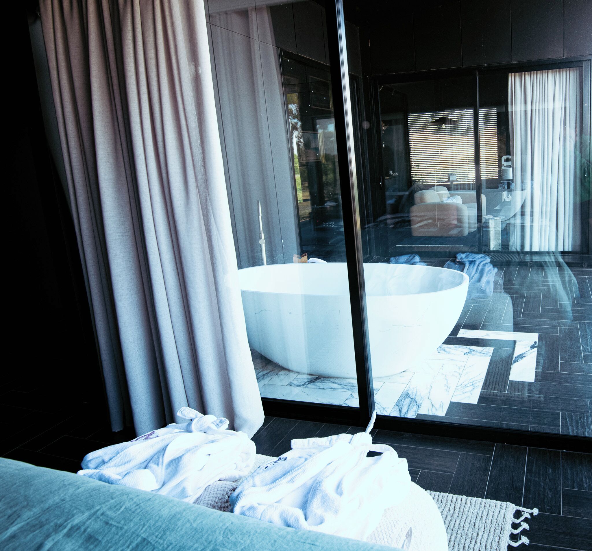 Un baño moderno con una bañera grande, un box de ducha de vidrio y vistas al exterior a través de la puerta de cristal.