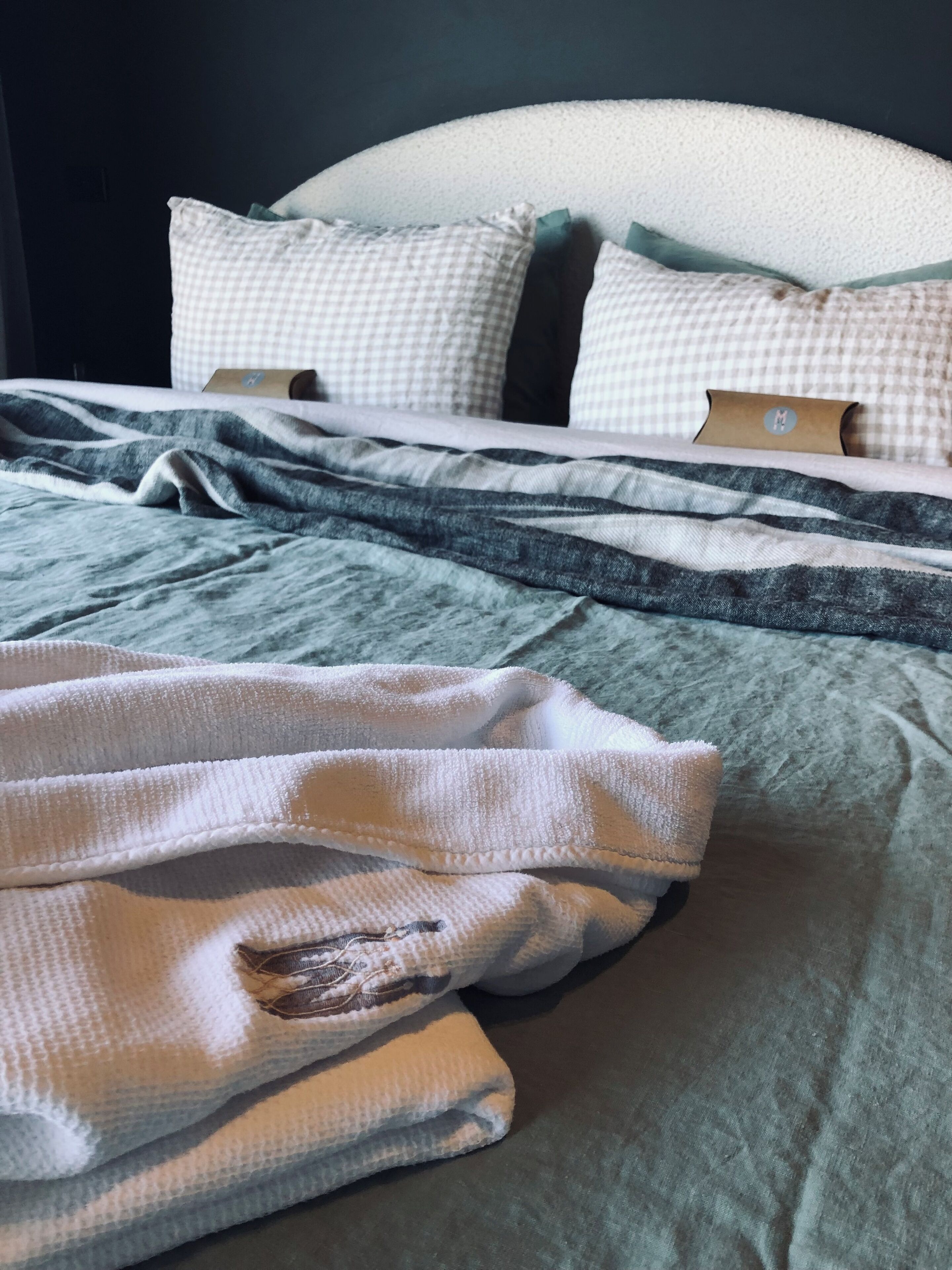 A neatly made bed with a checkered pillow and a folded blanket.