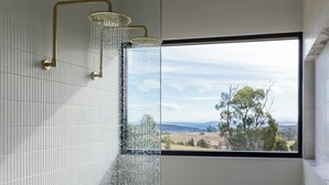Une douche avec vue sur un paysage, visible par une fenêtre.