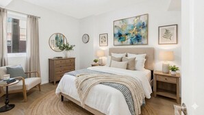Ein modernes Schlafzimmer mit einem großen Bett, Nachttischen, einem Sessel und Kunstwerken an den Wänden.