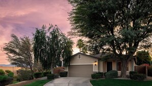 A residential house with a garage, driveway, and well-maintained lawn. - Blue Jay by Nest Villas | Idyllic Pool & Spa (Indio)