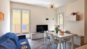 En moderne stue med sofa, fjernsyn, spisebord og stole.
