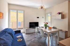 A modern living room with a sofa, TV, dining table, and chairs. - Levante - Mareri apartments (Imperia)